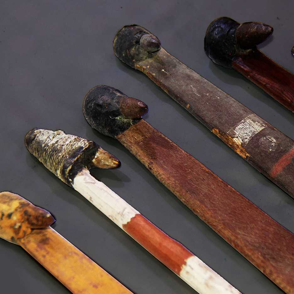 Close-up of several Aboriginal tools with black resin-coated tips and wooden handles, some painted or decorated, laid out in a row.