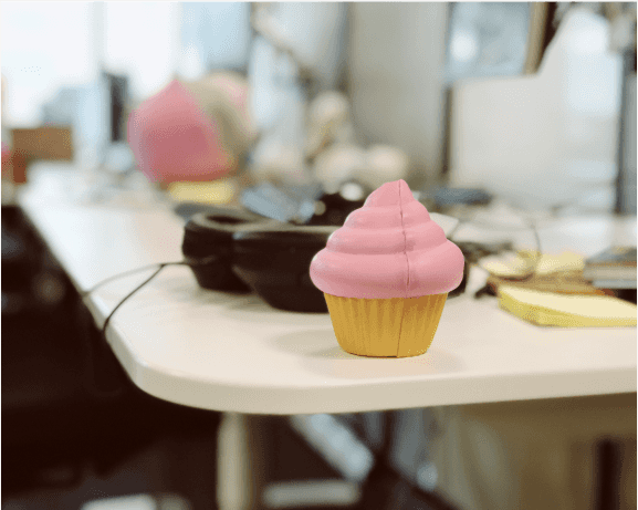A closeup of someone's desk. Headphones and a cupcake-shaped squeeze toy are in focus