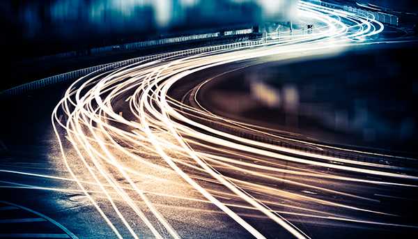 Long-exposure light trails in a curving pattern through a dim space