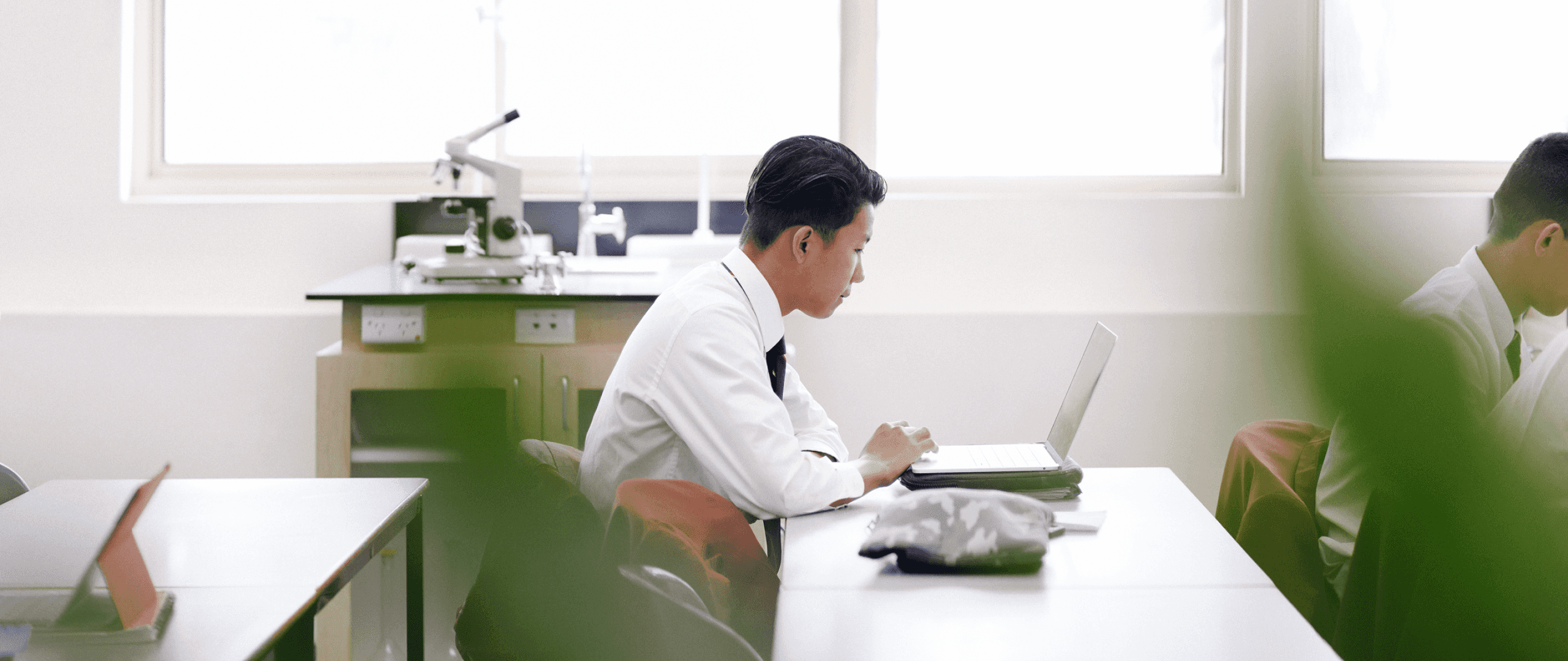 A student works quietly on his laptop in a science lab