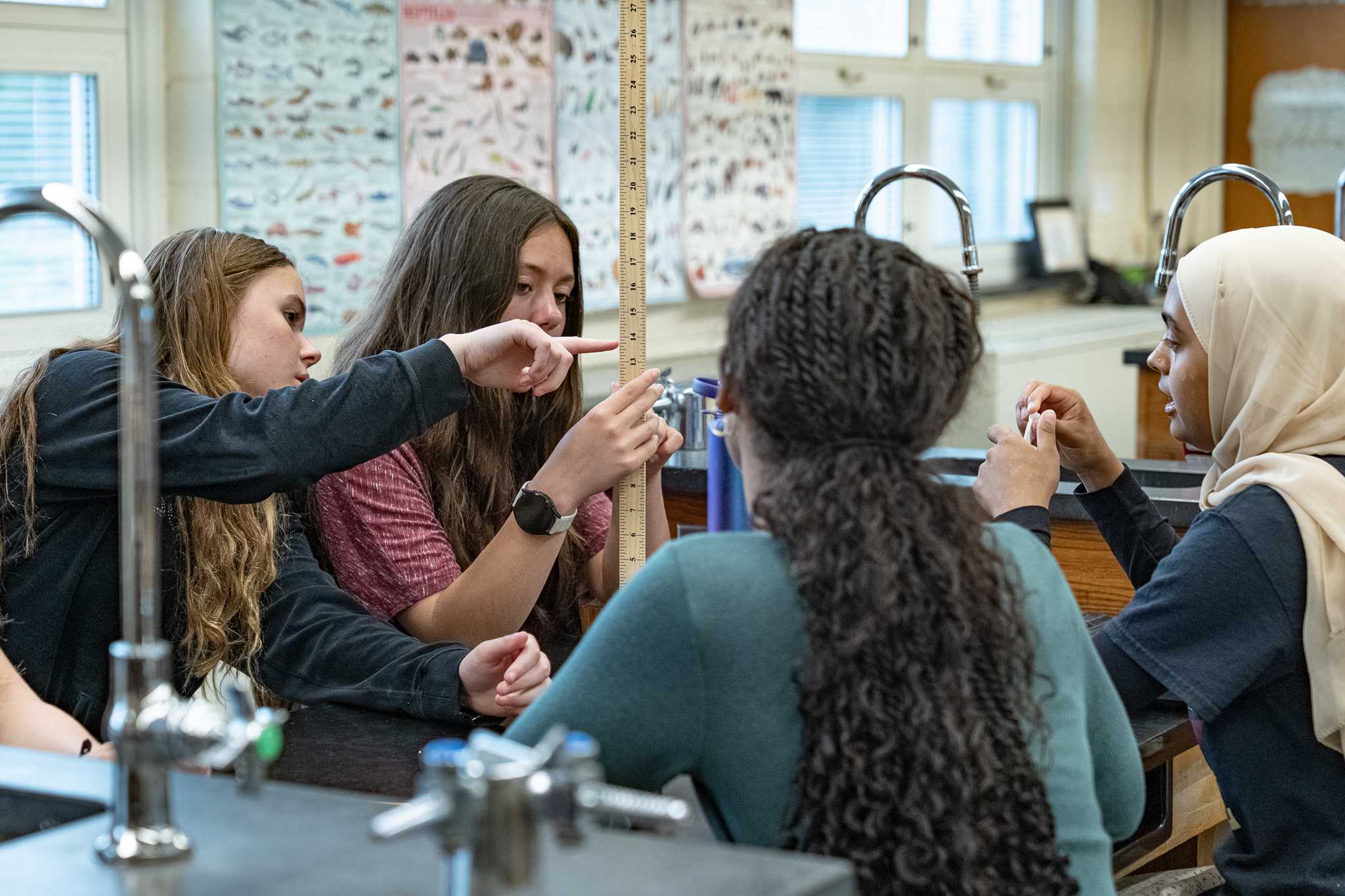 Students at a lab bench measuring with a ruler during a science investigation.