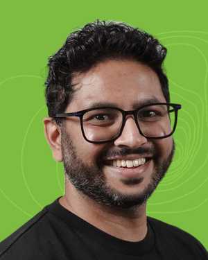 A black & white portrait of Stile team member Kunal Madhav smiling at the camera