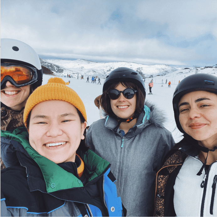 Four of Stile's staff smile at the camera in snow gear, with ski runs in the background