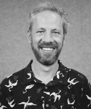 A black & white portrait of Stile team member Marcus Finlay smiling at the camera