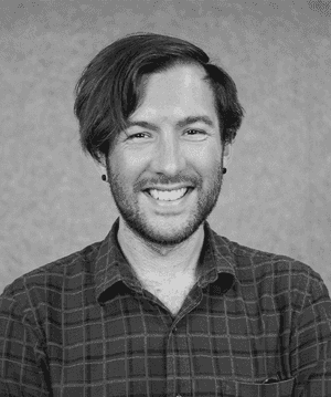A black & white portrait of Stile team member Ben Taylor smiling at the camera