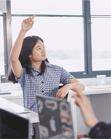 A student raises their hand, turning to face someone off camera