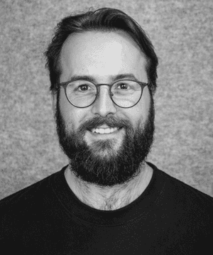 A black & white portrait of Stile team member Sean Hurley smiling at the camera