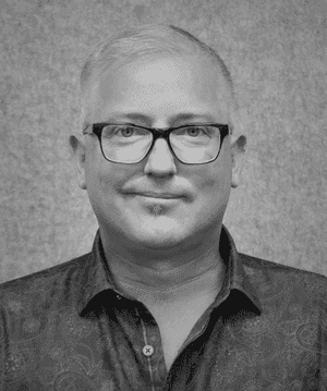 A black & white portrait of Stile team member Steve Dornan smiling at the camera