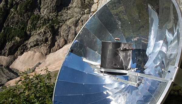 A concave reflective disk with a holder in the middle is placed outside on a rocky surface