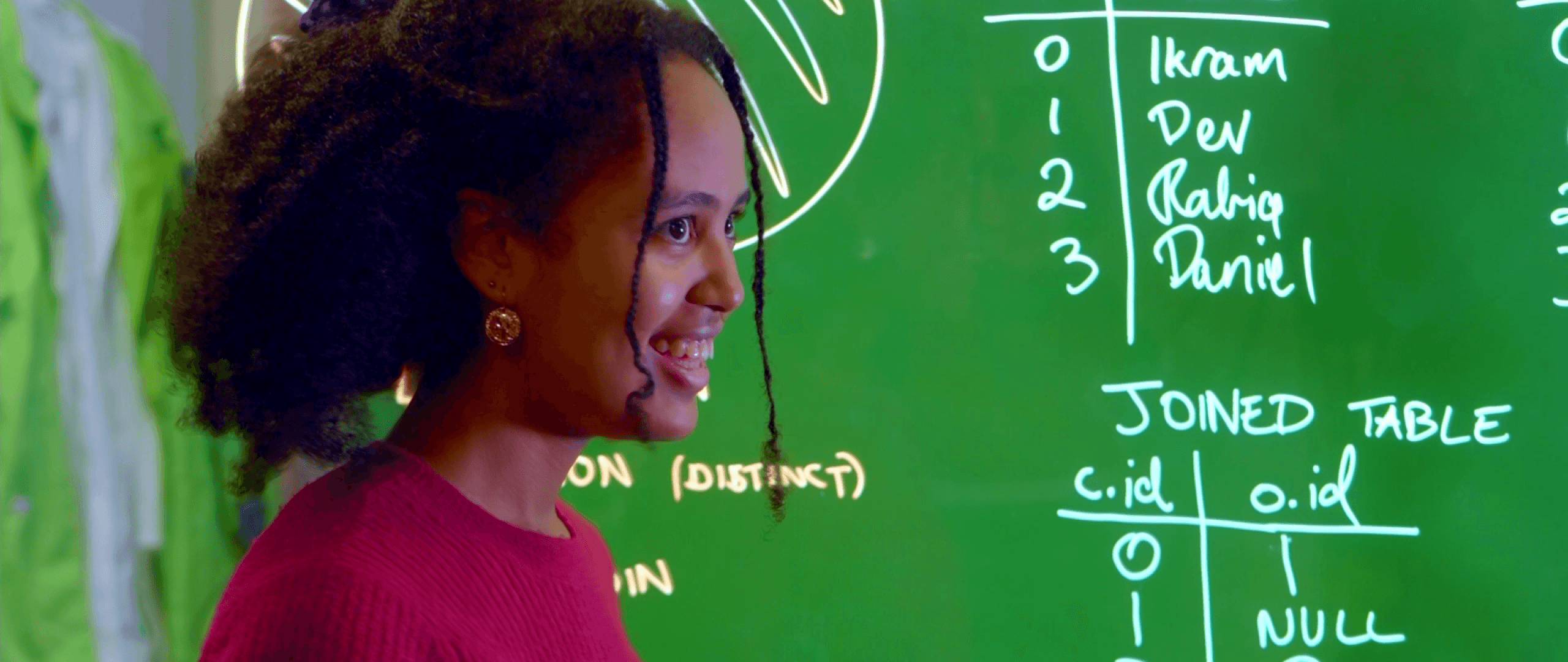 A young woman presents her ideas in front of a whiteboard displaying technical writing