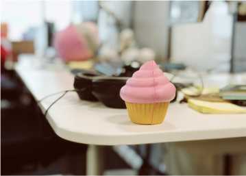 A closeup of someone's desk. Headphones and a cupcake-shaped squeeze toy are in focus