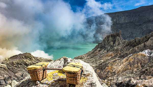 Two connected baskets sit on a rocky outcrop, with a lake giving of clouds of gas in the background