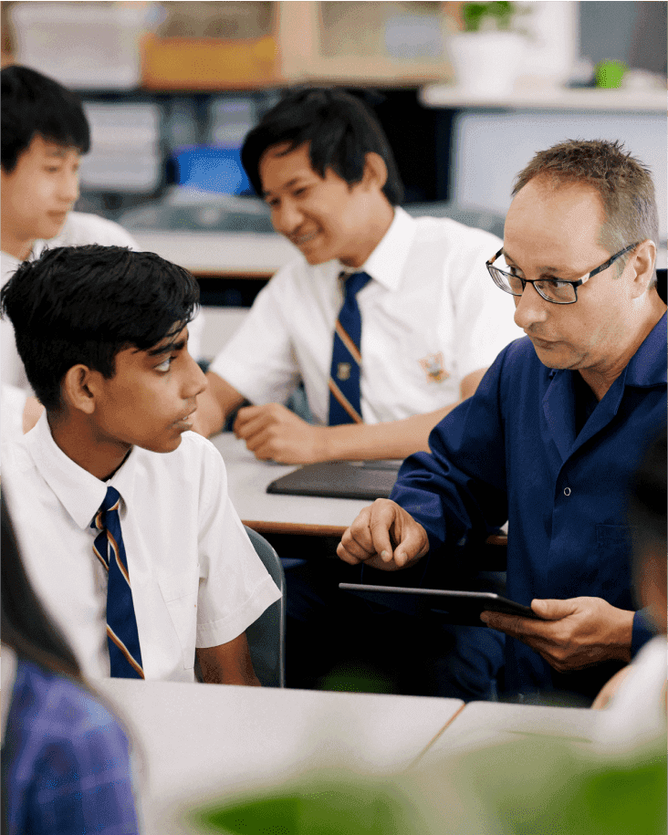 A teacher holding a tablet explains something to a student