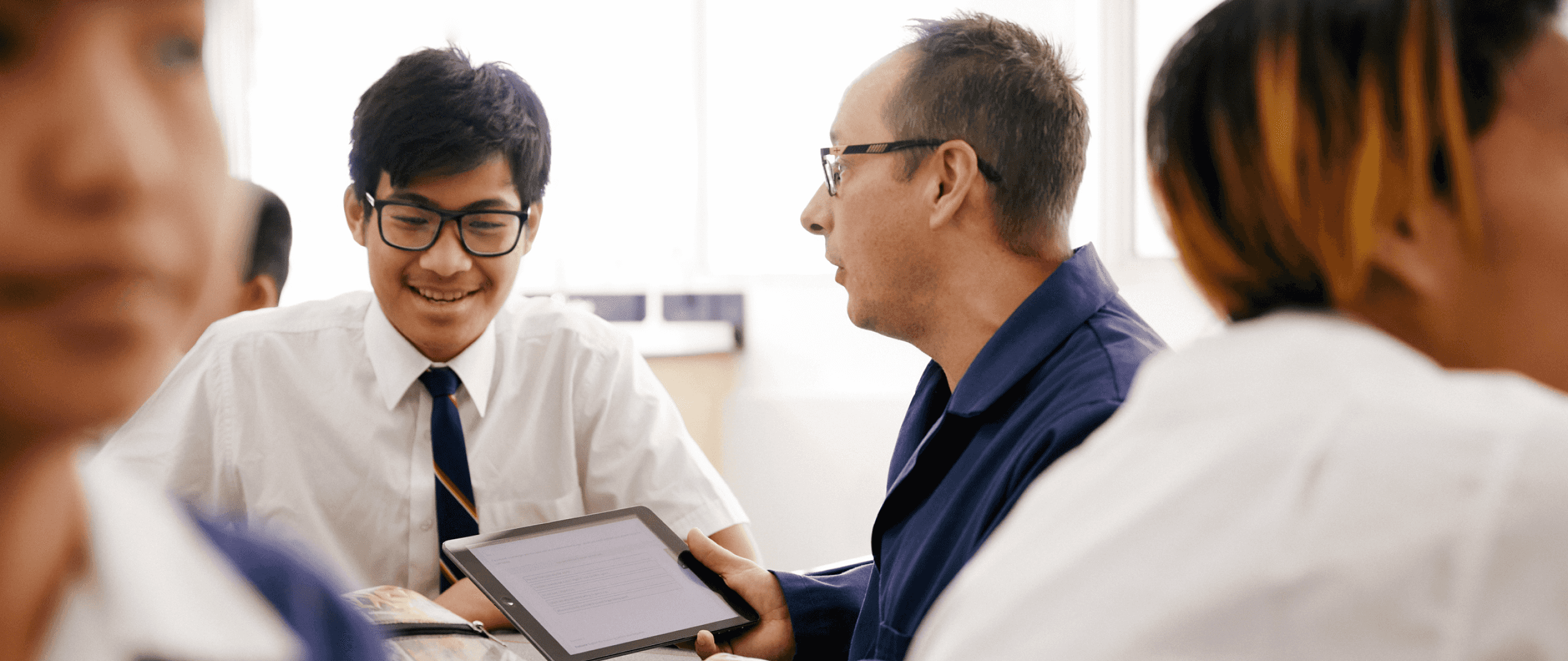 A teacher and student in the midst of a classroom discussing his work