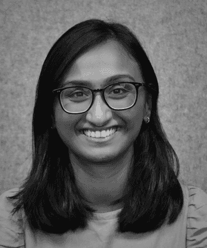 A black & white portrait of Stile team member Pooja Prabhakaran smiling at the camera