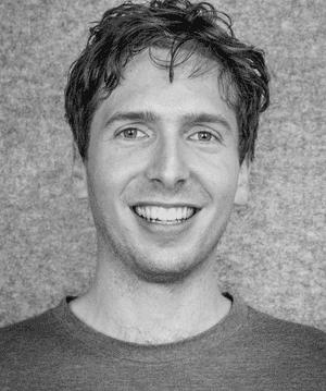 A black & white portrait of Stile team member Alex Finkel smiling at the camera