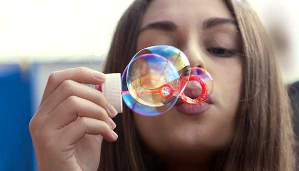 A closeup of a student blowing bubbles towards the camera